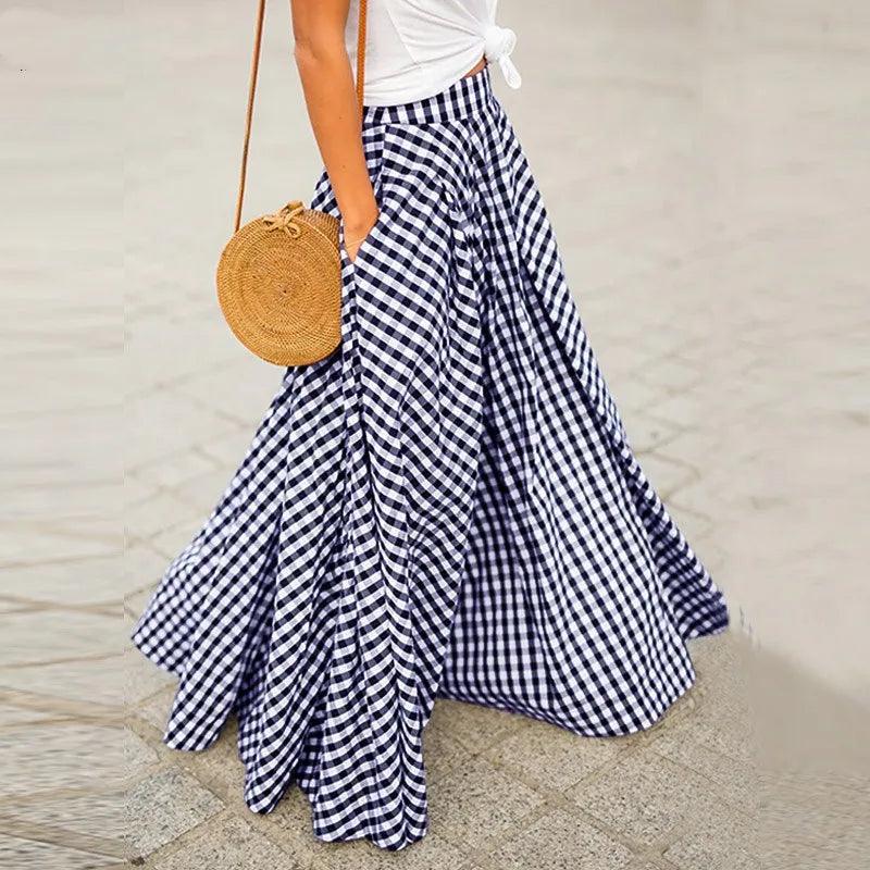 Person wearing a blue and white checkered skirt with a white top and holding a round woven bag on a neutral background.