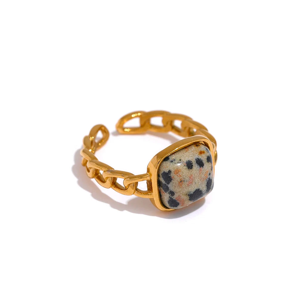 Gold ring with a speckled stone inlay on a white background