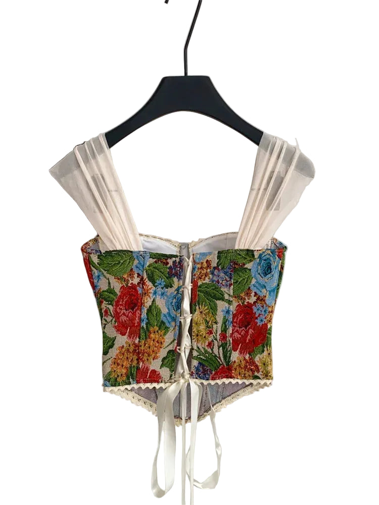 Floral crop top with sheer sleeves on a hanger against a white background
