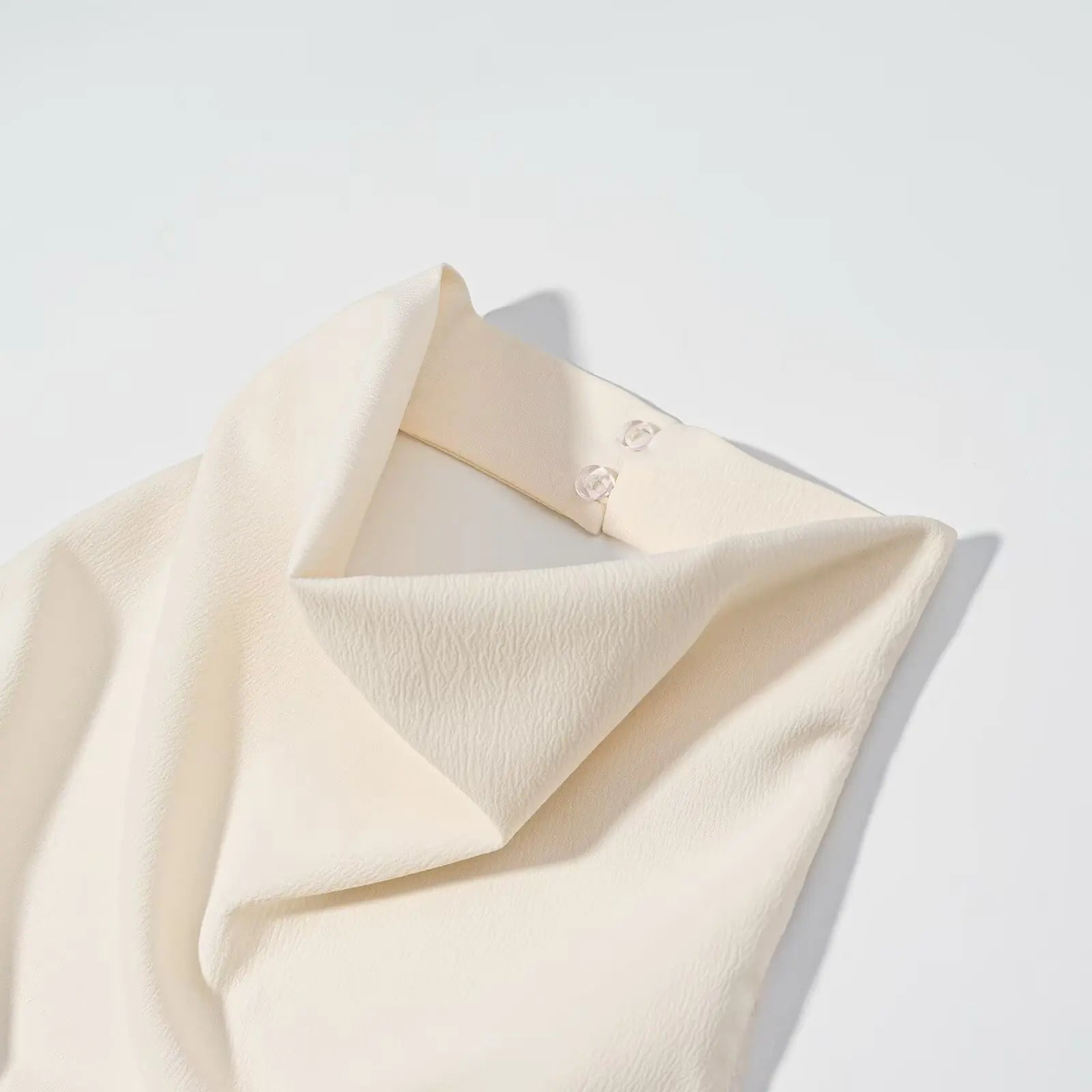 Folded cream-colored fabric on a light gray background