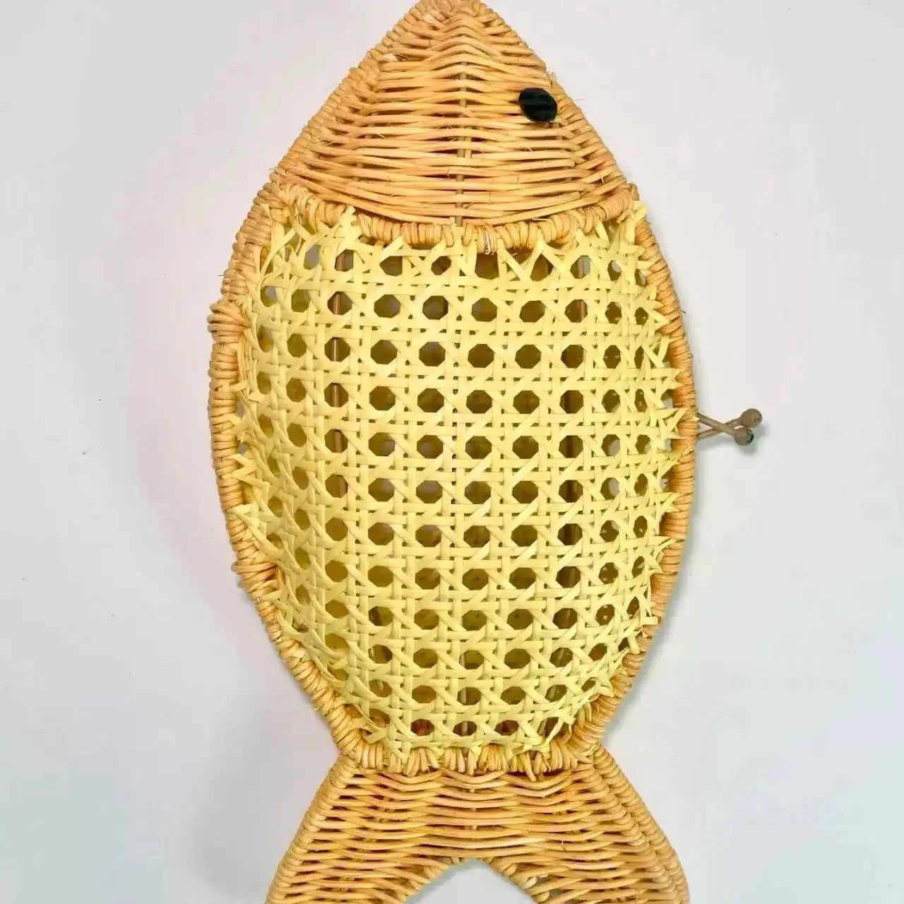 Woven fish-shaped decorative item with a yellow body and brown top and bottom on a light gray background.