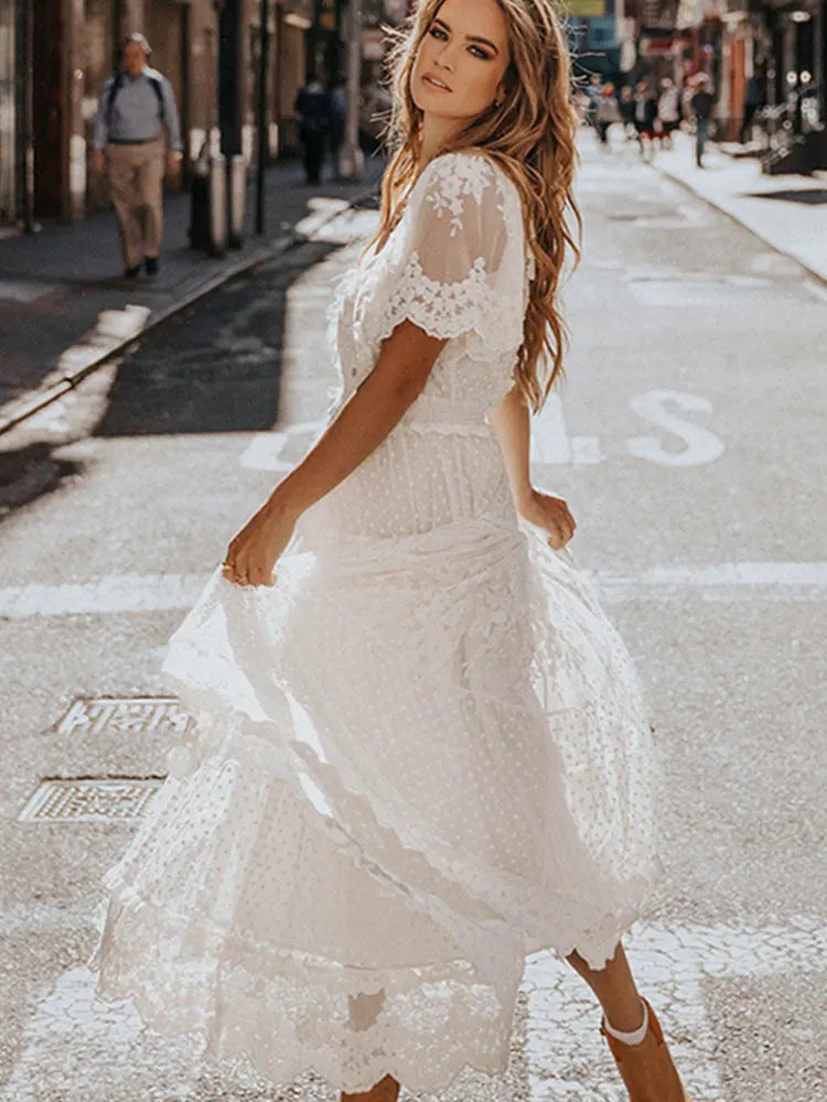 Woman in a white lace dress walking on a city street.