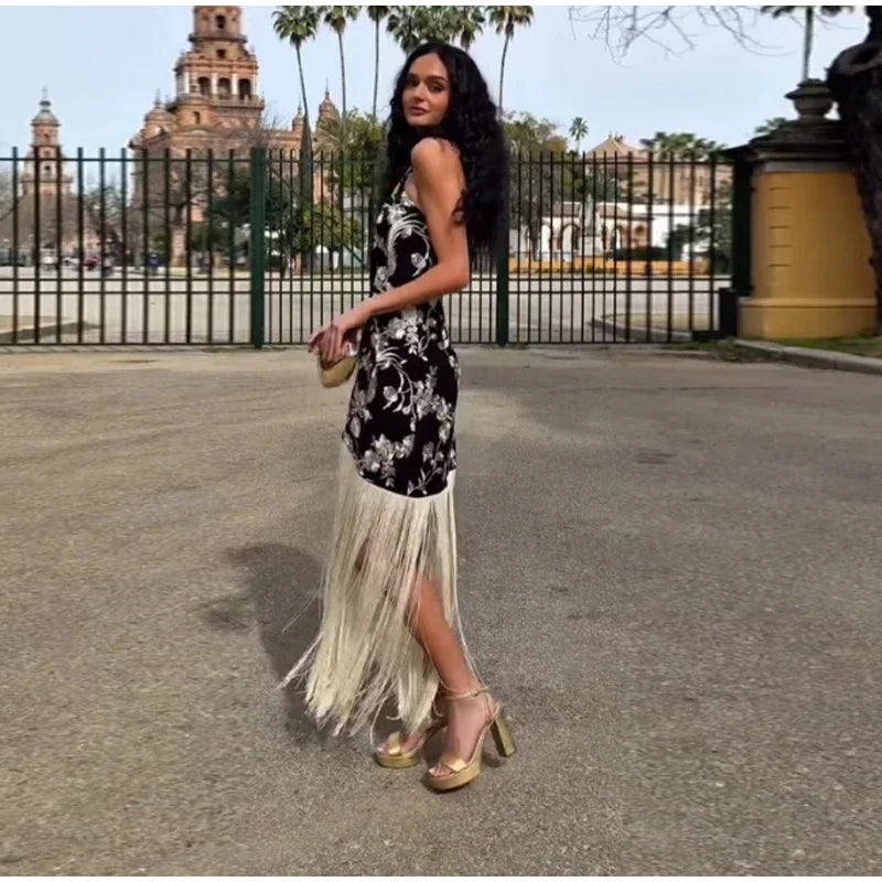 Woman in a floral dress with fringe walking outdoors with historical building in the background