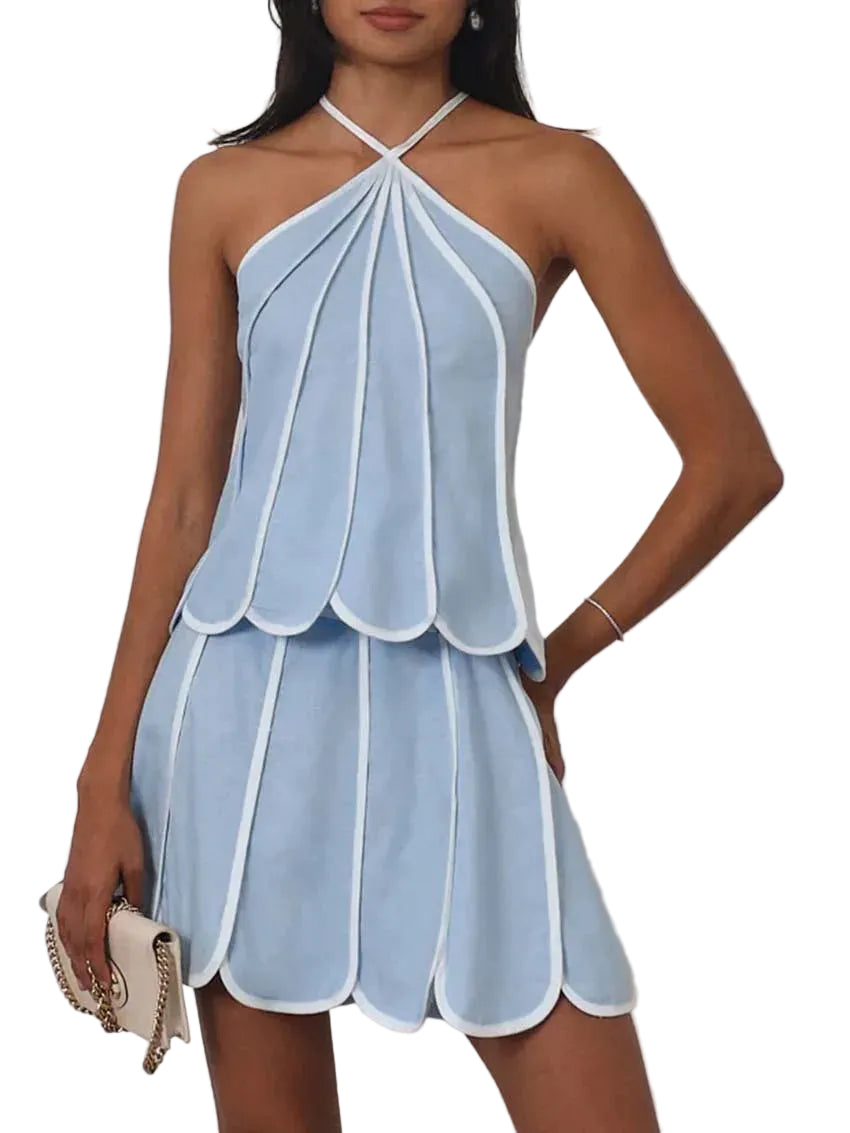 Woman wearing a light blue halter dress with white trim on a plain background