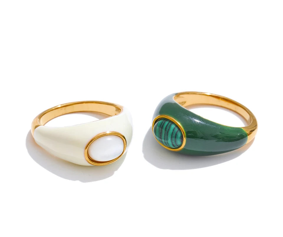 Two rings, one white and gold, the other green and gold, on a white background.