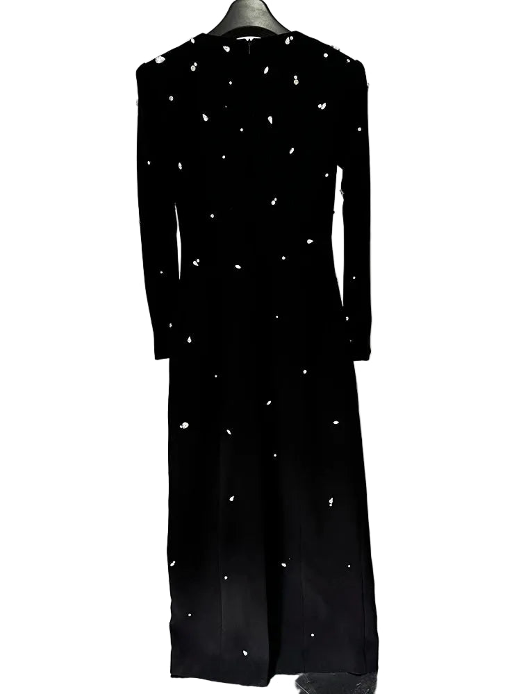 Black dress with white embellishments on a hanger against a white background