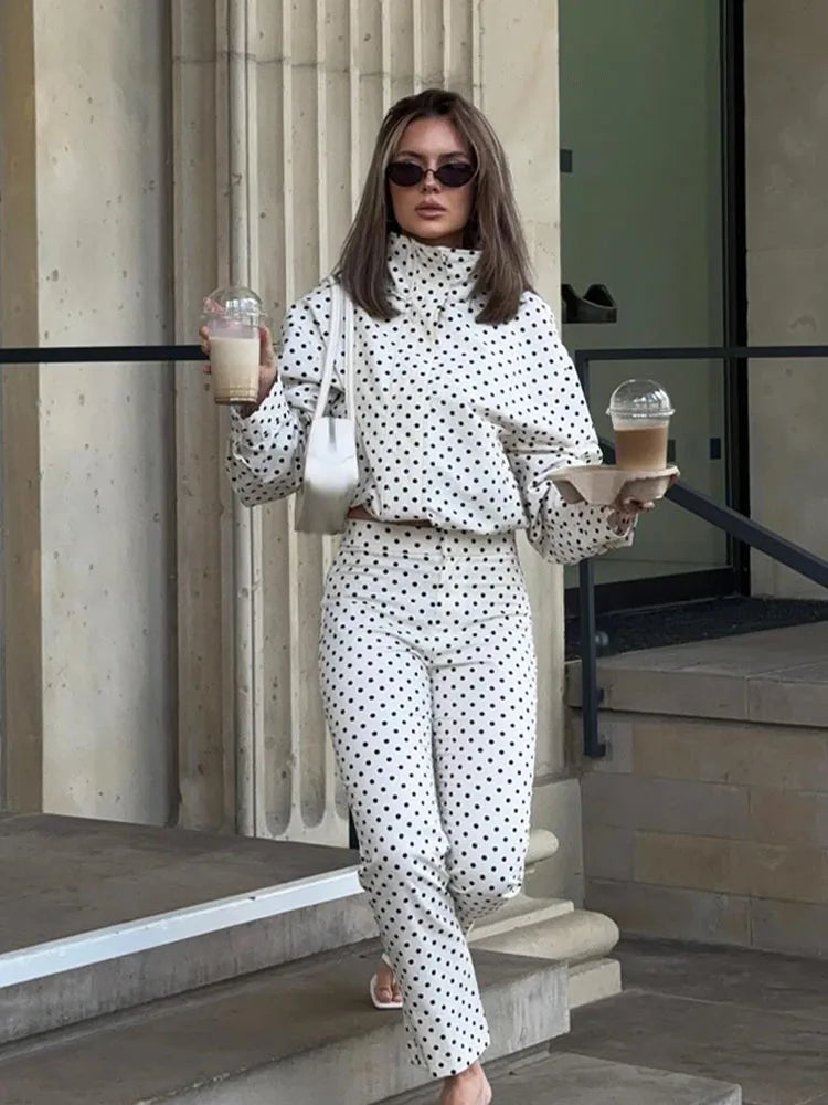 Woman in a polka dot outfit holding coffee cups outdoors.