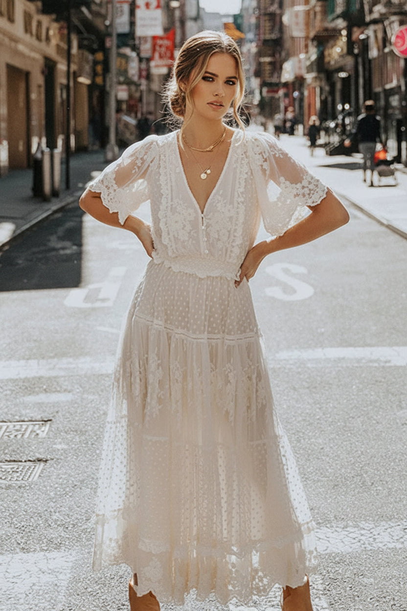 Woman in a white lace dress standing on a city street.